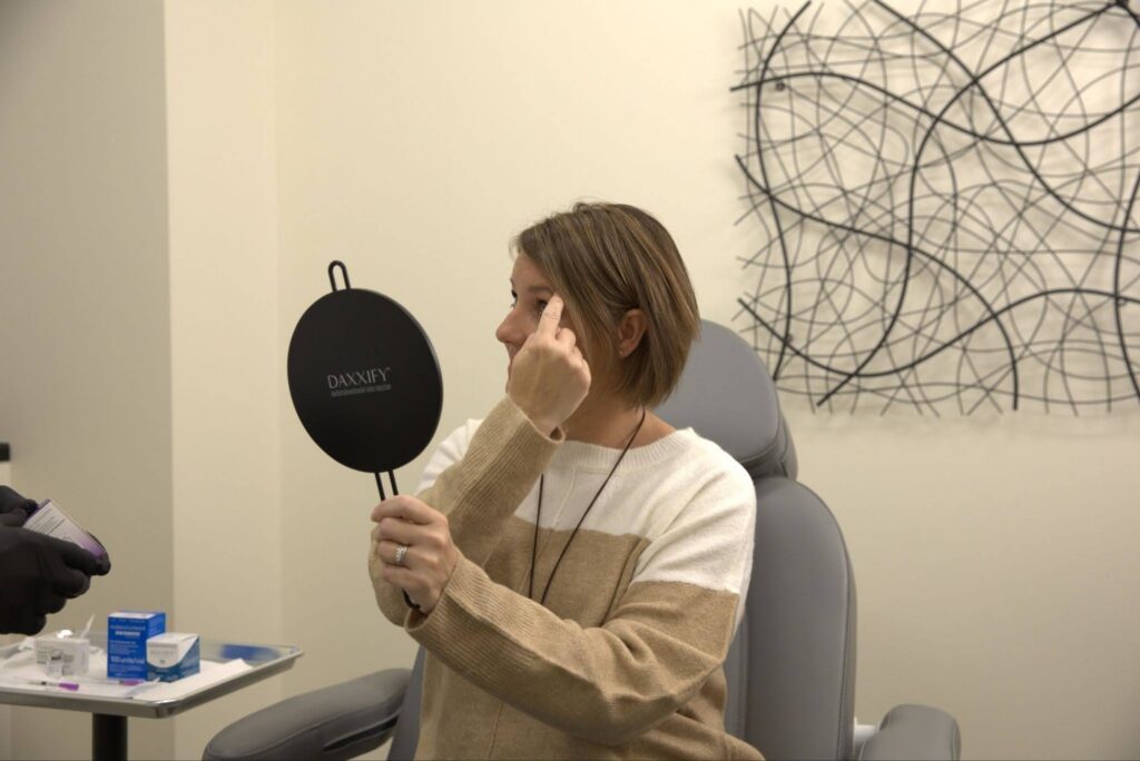 A woman points at her face during a 3D skin analysis in Brooklyn Park
