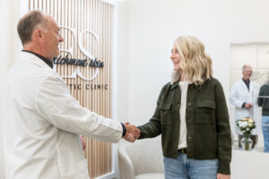 Enrichment Skin Solutions founder Michael Johnson warmly shakes hands with a female client, welcoming her to his health and wellness center in Brooklyn Park.