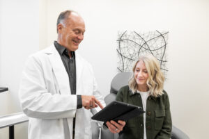 Michael Johnson, Enrichment Skin Solutions' Director of Procedural Medicine, shows a female client our hair loss solutions near Blaine.