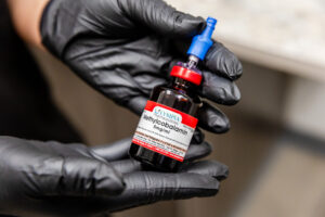 An Enrichment Skin Solutions provider holds a vial of vitamin B12 injections, one of our hair loss treatments for women near Maple Grove.