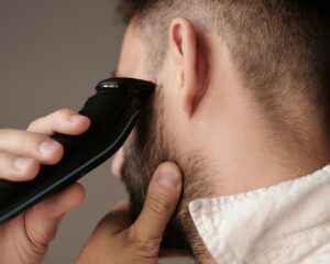 A male Enrichment Skin Solutions patient wears a white collared shirt and grooms his hair after experiencing men's hair restoration near Blaine.