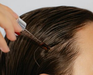 A female Enrichment Skin Solutions clients applies a hair oil to her scalp to support the results of her hair loss treatments for women near Maple Grove.